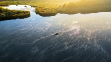 Güneşin doğuşunda nehirde balık tutan bir adamın hava aracı görüntüsü. Suda sis var.