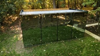 Doğadaki ayna yüzüyle glamping yapan bir cam ev manzarası. Çevrede yemyeşil orman