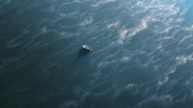 Bir teknede nehirde balık tutan bir adamın hava aracı dikey görüntüsü. Suda sis var.