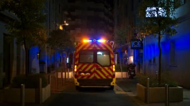 CANNES, FRANCE - 21 EYLÜL 2023: Sokakta geceleri yanıp sönen ışıklarla, dükkanları olan binalarla ambülans. Yavaş çekim