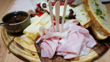 İtalyan et ve peynirini Focacia ekmeği, prosciutto, salam, zeytin ve tatlı soslu sebzelerle kapatın.