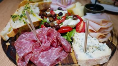 İtalyan et ve peynirini Focacia ekmeği, prosciutto, salam, zeytin ve tatlı soslu sebzelerle kapatın.