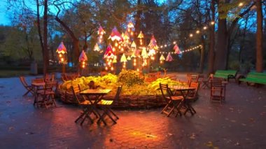 Moldova, Chisinau 'da mavi gökyüzü ile altın saat içinde çiçek ışıkları olan bir parkta kahve masaları.