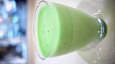 Kahve dükkanındaki yeşil kibrit latte bardağının dikey görüntüsü.