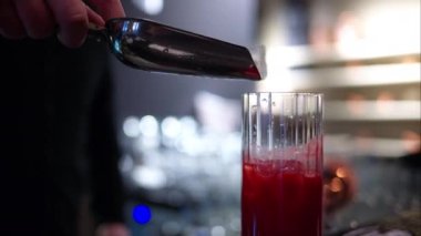 Barmen barda buzlu kırmızı limonata kokteyli yapıyor.