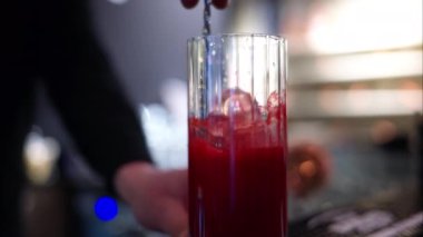 Barmen barda buzlu kırmızı limonata kokteyli yapıyor.