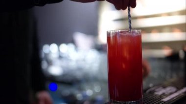 Barmen barda buzlu kırmızı limonata kokteyli yapıyor.
