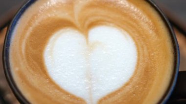 Kahverengi kapuçino, bir kahve dükkanının tepesinde beyaz bir kalple yakın plan.