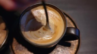 Kahveye beyaz kalpli esmer şeker karıştıran bir kadın.