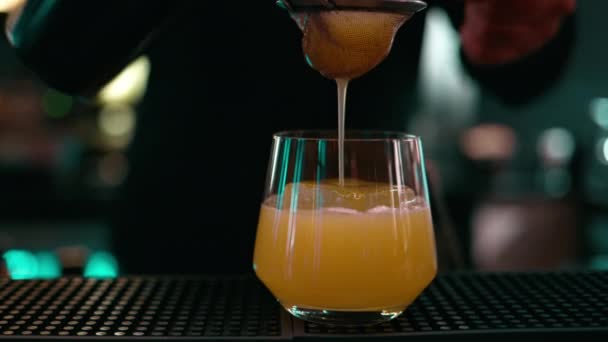 调酒师将威士忌鸡尾酒倒入装有摇臂搅拌机冰块的杯子中 — 图库视频影像