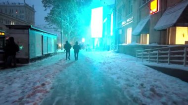Chisinau, Moldova - 20 Kasım 2023: Pini ve mavi neon ışıklarıyla şehir merkezinde yürüyen insanlar