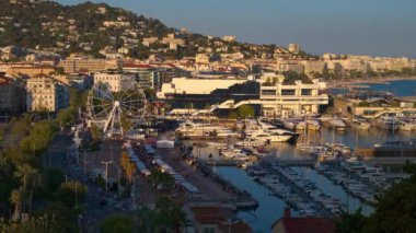 Yat ve yelkenlilerle çevrili dönme dolabı olan eski bir liman. Arka planda Cannes şehri
