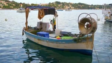 Sakin bir limana demirlemiş küçük bir balıkçı teknesi. Yatlar arka planda