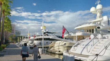 GOLFE-JUAN, FRANCE - 4 Eylül 2023: güneşli bir günde Camille Rayon Limanı lüks yatlarla doluydu. Limanda yürüyen insanlar