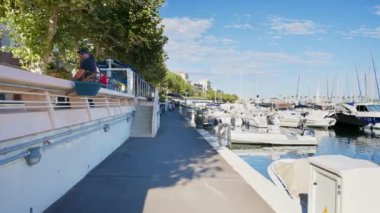 JUAN LES PINS, FRANCE - 4 Eylül 2023: Lüks yatlarla ve yelkenli teknelerle dolu liman yakınlarında yürüyen insanlar