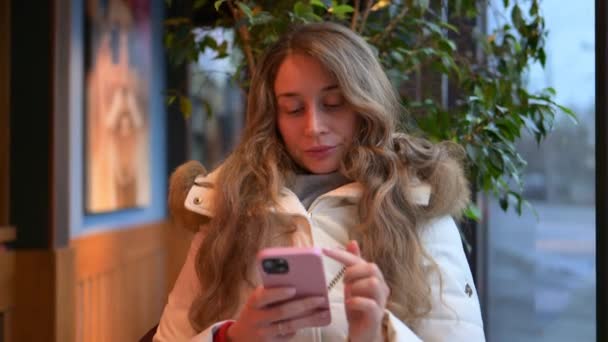 穿着冬衣的妇女在一个平台上用手机工作 动作缓慢 — 图库视频影像