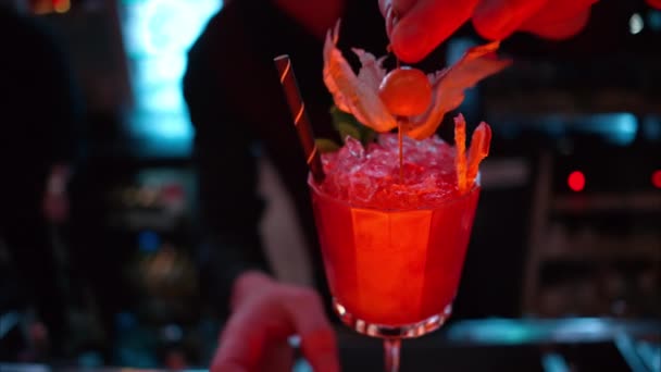 酒吧招待晚上在有霓虹灯的酒吧里倒入橙红色的鸡尾酒和冰块 — 图库视频影像
