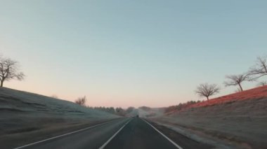 Sabahın ilk ışıklarıyla araba penceresi ve yolu görüyorum.