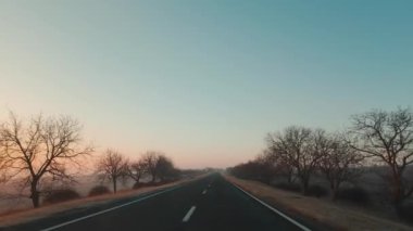 Sabahın ilk ışıklarıyla araba penceresi ve yolu görüyorum.