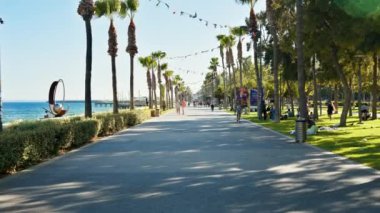 Limasol, Kıbrıs - 07 Ağustos 2023: İnsanlar gün ışığında Molos parkındaki gezinti alanında yürüyor