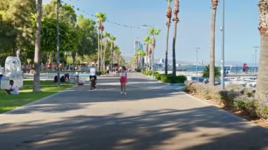 Limasol, Kıbrıs - 07 Ağustos 2023: İnsanlar gün ışığında Molos parkındaki gezinti alanında yürüyor