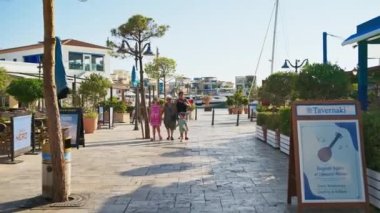 Limasol, Kıbrıs - 07 Ağustos 2023: İnsanlar güneş ışığında restoranların yakınındaki Eski Liman 'ın gezinti alanında yürüyorlar