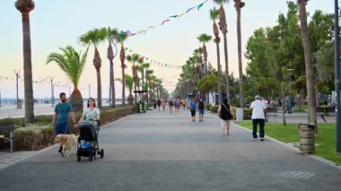 Limasol, Kıbrıs - 07 Ağustos 2023: Akşam saatlerinde Molos parkındaki gezinti alanında yürüyen insanlar