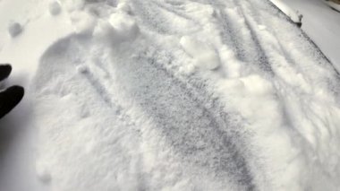 Kışın donmuş kardan arabanın ön camını açan kahverengi deri eldivenli adam.