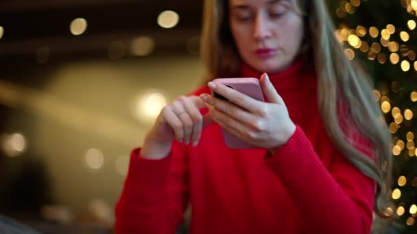 Woman Red Sweater Using Smartphone Green Tree Lights Background — Stock Video