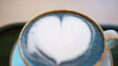 Seramik bardakta kalp şeklinde köpüklü mavi kibrit latte.