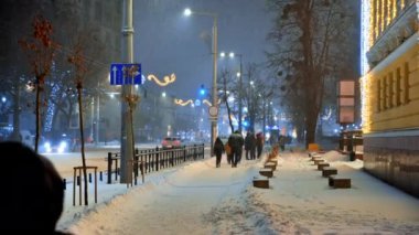 Chisinau, Moldova - 09 Ocak 2024: İnsanlar akşam saatlerinde şehir merkezinde aydınlık bir sokakta yürüyorlar. Noel süsleri. Mavi saat