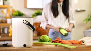 Gübre kutusunda geri dönüşüm için sebze kabuğu hazırlayan genç bir kadın. Ev hanımı yemek pişiriyor ve organik atıkları evdeki Bokashi konteynırında çürütüyor. Ekolojik ve sürdürülebilirlik kavramı