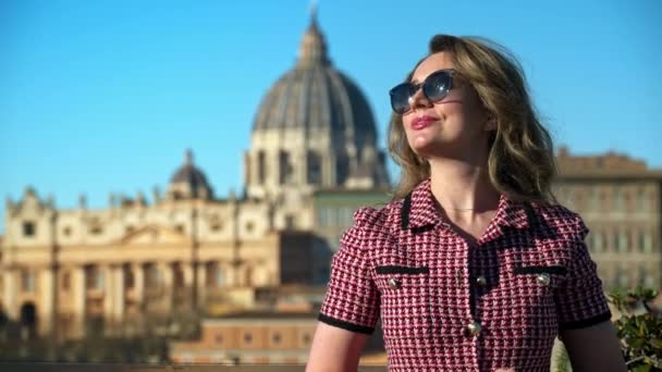 戴太阳镜的金发年轻女子对梵蒂冈的背景笑了 日落时的圣彼得大教堂意大利罗马 — 图库视频影像