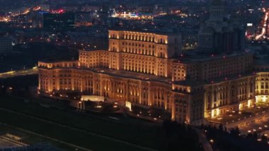 Akşam Bükreş 'teki Parlamento Sarayı' nın aydınlanmış hava aracı görüntüsü. Çevrede çok sayıda bölge var. Romanya