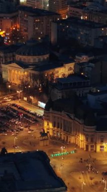 Gece Carol I Üniversitesi Vakfı 'nın dikey hava aracı görüntüsü. Carol 'ın olduğu ana bina önünde heykeller, yollar ve binalar. Bükreş kenti ve Romanya aydınlandı