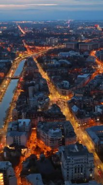 Akşamları aydınlanan şehrin dikey hava aracı görüntüsü. Trafiği değiştiriyorum. Romanya 'nın Bükreş kentinde mavi saat