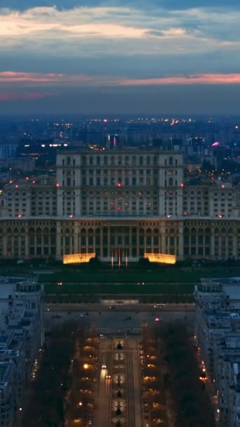 傍晚时分 布加勒斯特市中心被照亮的议会宫的垂直空中超光速掠过无人机画面 周围多个地区 罗马尼亚 — 图库视频影像