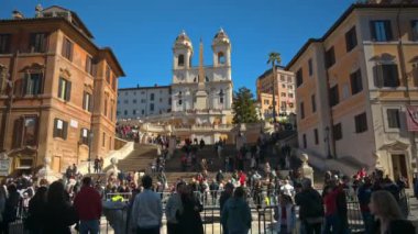 Roma, İtalya - 14 Şubat 2024: İspanyol meydanında barok tarzı Kayık Çeşmesi 'nin yanında gün ışığında yürüyen turistler. Arka planda Santissima Kilisesi Trinit dei Monti