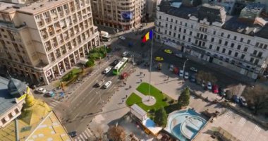 Bükreş, Romanya - 03 Mart 2024: Trafiği hareket ettiren ve gün ışığında yürüyen insanlarla şehir merkezindeki bir kavşağın insansız hava aracı görüntüsü. Ulusal bayrak sallıyor