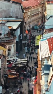 Bükreş, Romanya - 03 Mart 2024: Eski kentteki tarihi binalar ve ticari dükkanlar arasında yürüyen insanların dikey hava aracı görüntüsü
