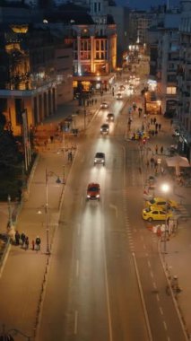 Bükreş, Romanya - 03 Mart 2024: Akşamları hareket halindeki trafik ile aydınlanan yolun dikey hava aracı görüntüsü. Mavi saat