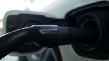 Elektrikli araba şarj cihazı. Arka planda bulanık şehir görüntüsü.