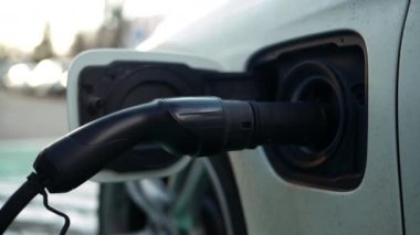 Elektrikli araba şarj cihazı. Arka planda bulanık şehir görüntüsü.