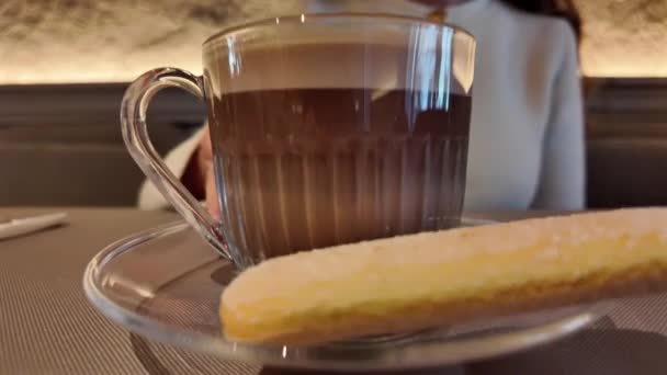 一个女孩在咖啡店里用饼干搅拌一杯咖啡的特写镜头 — 图库视频影像