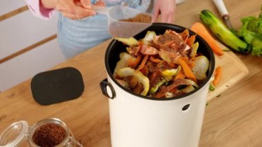 Kadın sebze kabuklarına Bokashi kepeği dökerek organik atıkları geri dönüştürüyor. Mutfakta.