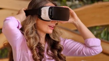 Kadın VR kulaklığı takıyor ve eğleniyor.