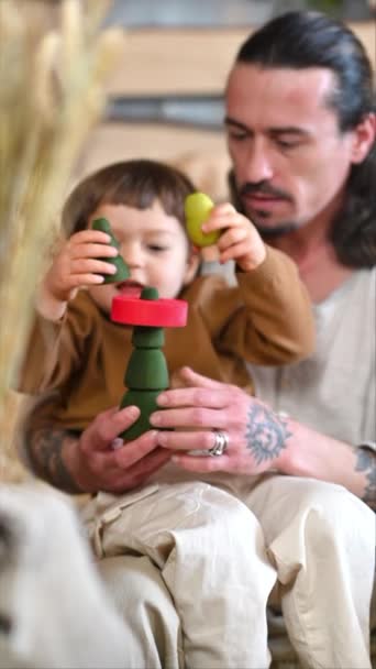 父親は彼の息子と遊んでいます カラフルで生態学的な木製のおもちゃは 納屋で 正方形の干し草のベールの近く — ストック動画