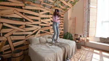 Kadın VR kulaklığından yatağa atlıyor.