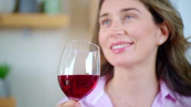 Mutfakta kırmızı şarap içen bir kadın.