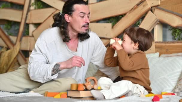 父亲和儿子在床上玩五彩缤纷的生态木制玩具 — 图库视频影像